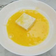 步骤图:鸡蛋打散装在平盘中，把粘好淀粉的豆腐两面都均匀粘上