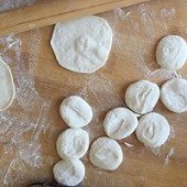 步骤图:把小剂子分别压扁，开始擀皮。饺子皮中间要稍稍比边缘
