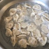 步骤图:水开后下饺子，用勺子蹭一下锅底，以免粘锅。饺子煮起