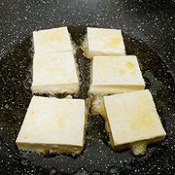 步骤图:锅内倒入适量油，放入豆腐块，小火慢煎。
